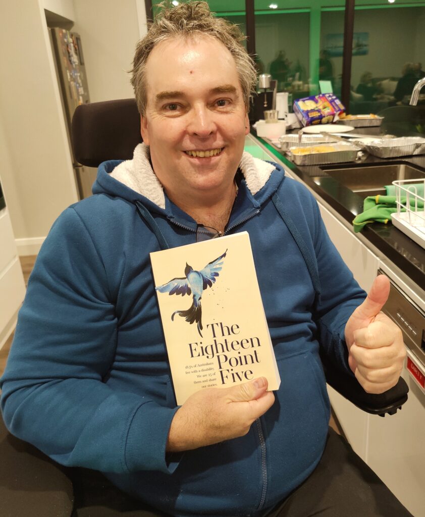 Biographies about famous people - john duthie wearing a teal hoodie and holding the book with his thumbs up